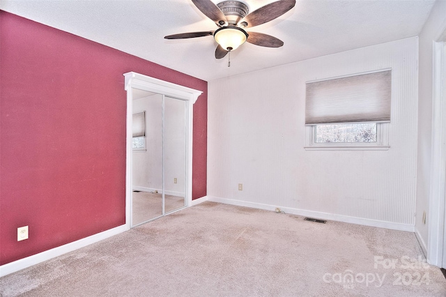 unfurnished bedroom with ceiling fan, light carpet, and a closet