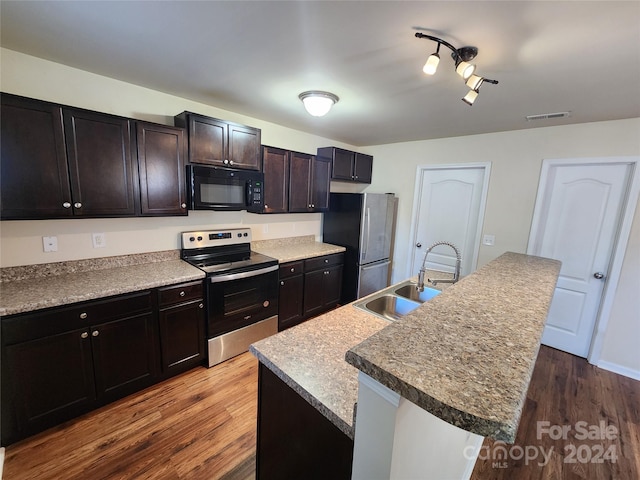 kitchen featuring a center island with sink, sink, wood-type flooring, and stainless steel appliances