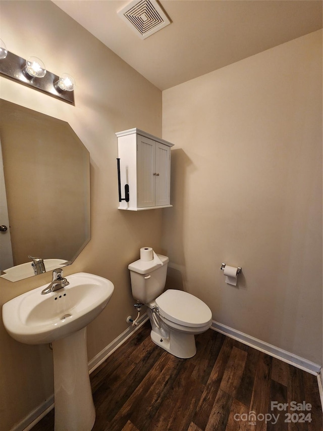 bathroom with toilet, wood-type flooring, and sink