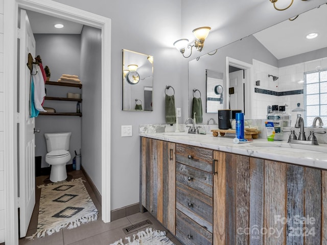 bathroom featuring a tile shower, tile patterned floors, lofted ceiling, toilet, and vanity