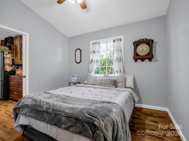 bedroom featuring dark hardwood / wood-style flooring, vaulted ceiling, and ceiling fan