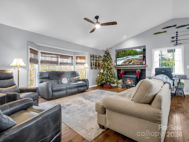 living room featuring hardwood / wood-style floors, lofted ceiling, ceiling fan, and a wood stove