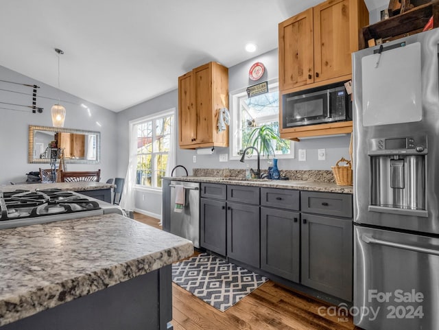 kitchen featuring pendant lighting, sink, vaulted ceiling, dark hardwood / wood-style flooring, and stainless steel appliances