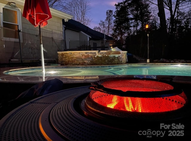 pool at dusk featuring a hot tub