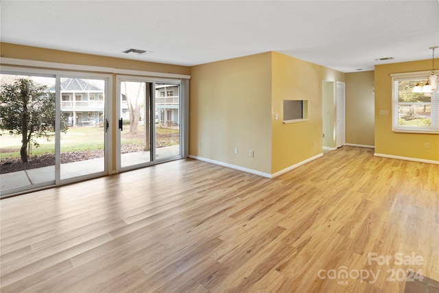 unfurnished room with light hardwood / wood-style floors and a notable chandelier