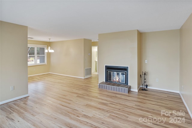 unfurnished living room featuring an inviting chandelier and light wood-type flooring