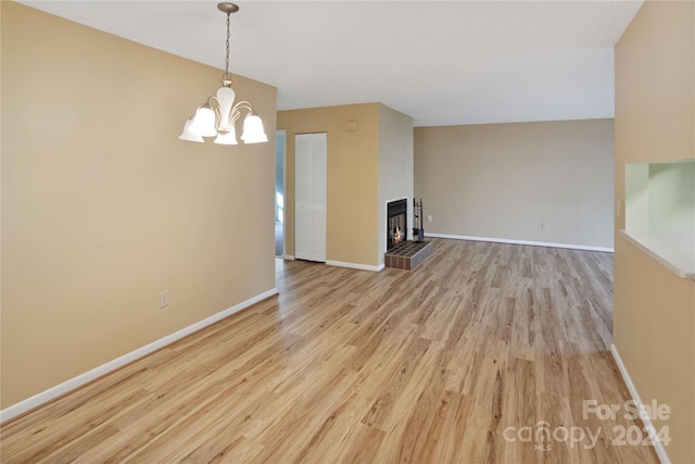 unfurnished living room featuring a multi sided fireplace, a chandelier, and light hardwood / wood-style flooring