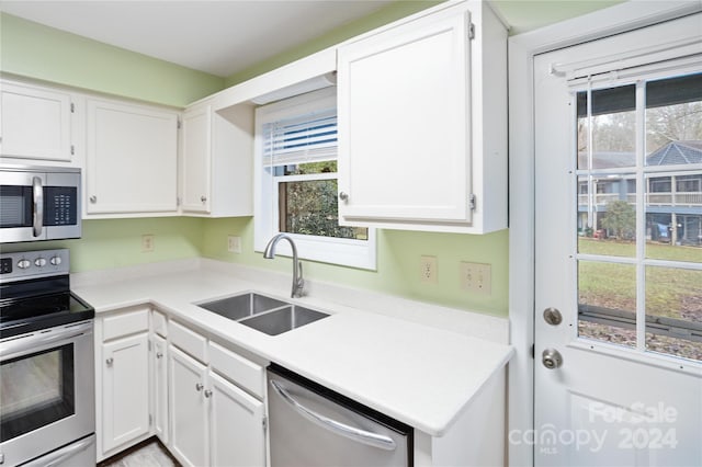 kitchen featuring appliances with stainless steel finishes, white cabinetry, and sink