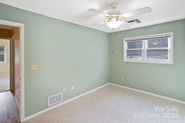 carpeted spare room featuring plenty of natural light and ceiling fan