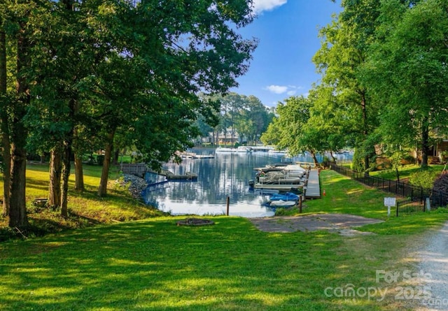 view of property's community with a boat dock, a yard, and a water view