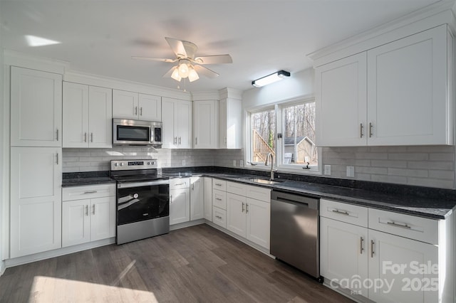 kitchen with ceiling fan, sink, dark wood-type flooring, stainless steel appliances, and white cabinets