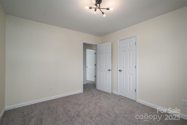 unfurnished bedroom featuring carpet flooring and a chandelier