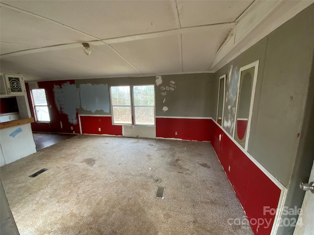 carpeted empty room featuring vaulted ceiling