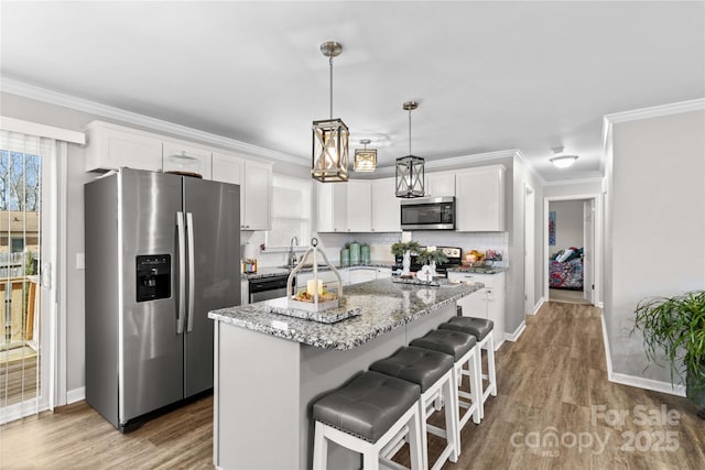 kitchen with stainless steel appliances, a center island, pendant lighting, and white cabinets