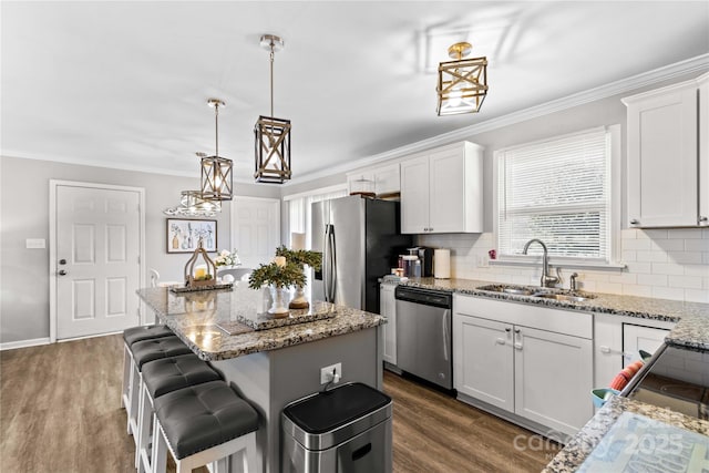 kitchen with white cabinetry, sink, stainless steel appliances, and a kitchen island