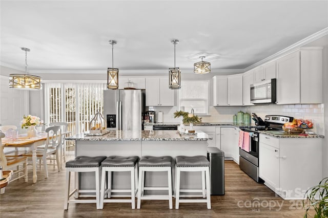 kitchen featuring white cabinetry, a kitchen island, a wealth of natural light, pendant lighting, and stainless steel appliances