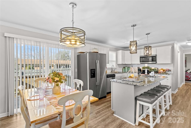 kitchen featuring pendant lighting, white cabinetry, a center island, stainless steel appliances, and crown molding