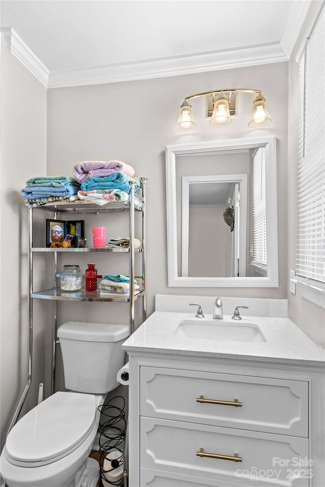 bathroom with ornamental molding, vanity, and toilet