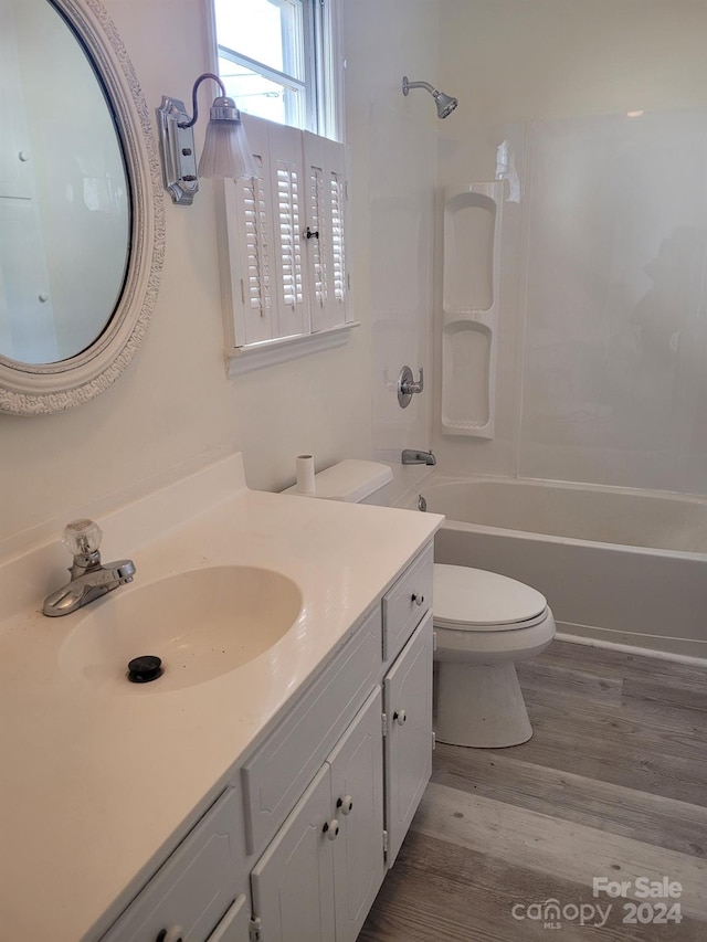 full bathroom with hardwood / wood-style floors, vanity,  shower combination, and toilet