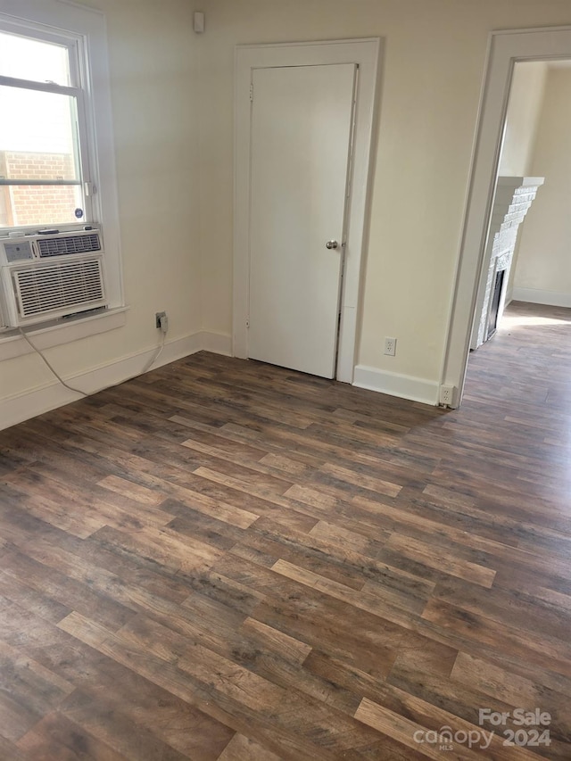 empty room featuring cooling unit, dark hardwood / wood-style flooring, and a fireplace