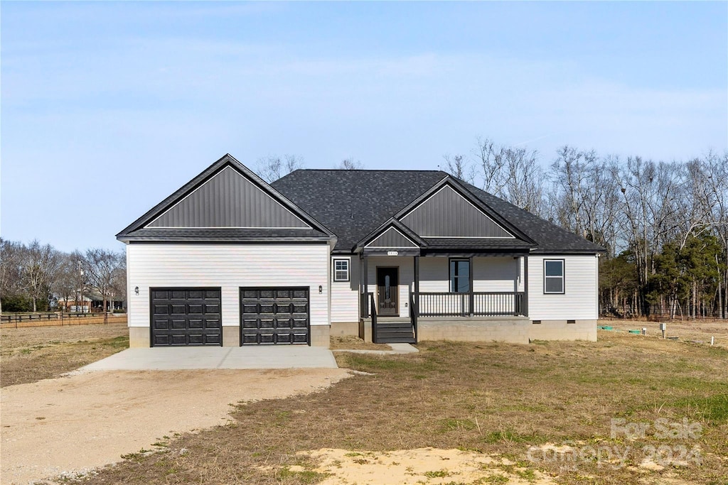 view of front of house featuring a porch, a garage, and a front lawn