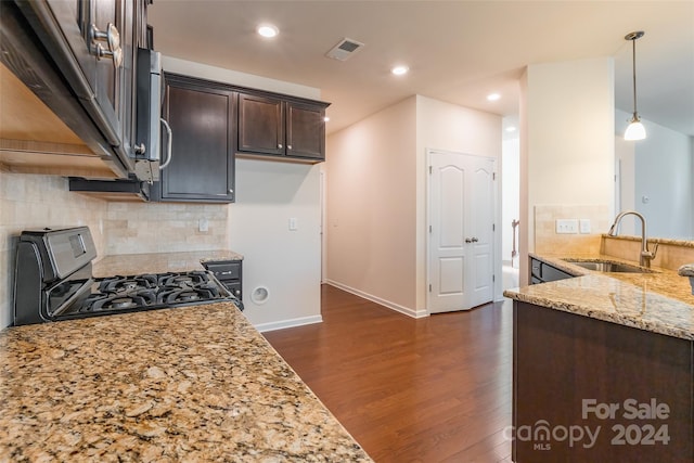 kitchen with light stone countertops, black gas range oven, dark brown cabinetry, sink, and hanging light fixtures