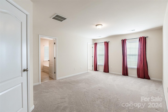 unfurnished bedroom featuring connected bathroom and light colored carpet