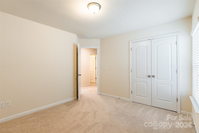 unfurnished bedroom featuring multiple windows, light carpet, and a closet