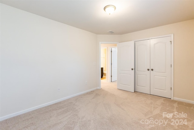 unfurnished bedroom featuring light colored carpet and a closet