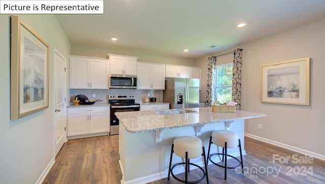 kitchen with appliances with stainless steel finishes, a center island with sink, and white cabinetry