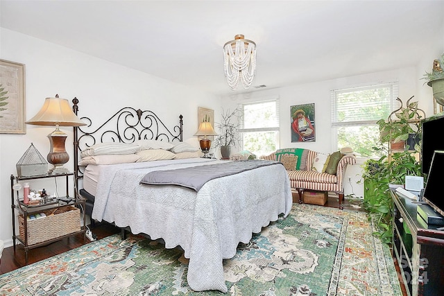 bedroom with dark hardwood / wood-style floors and an inviting chandelier