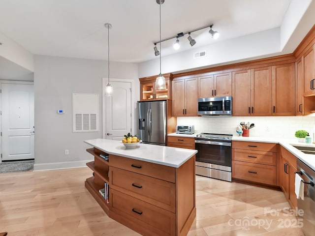 kitchen featuring sink, light wood-type flooring, appliances with stainless steel finishes, tasteful backsplash, and decorative light fixtures