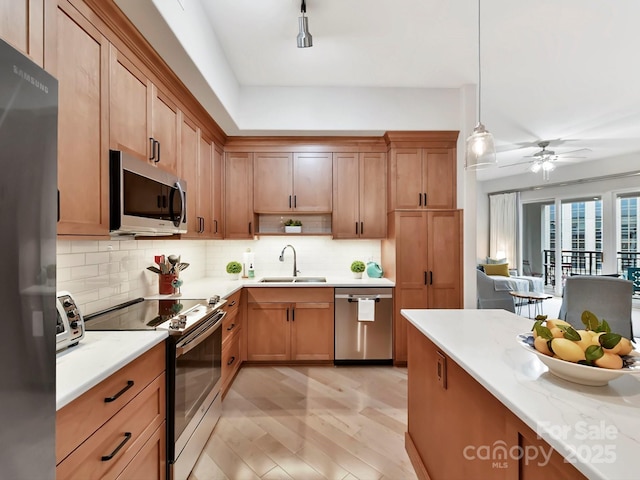 kitchen with backsplash, stainless steel appliances, ceiling fan, sink, and decorative light fixtures