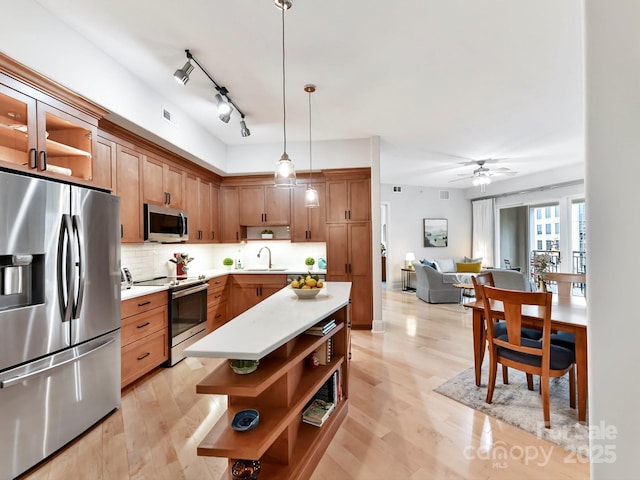 kitchen featuring appliances with stainless steel finishes, tasteful backsplash, ceiling fan, sink, and pendant lighting