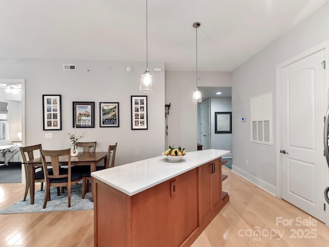 kitchen featuring decorative light fixtures, a kitchen island, light wood-type flooring, and ceiling fan