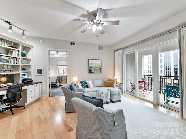 living room with a wealth of natural light, ceiling fan, track lighting, and light wood-type flooring