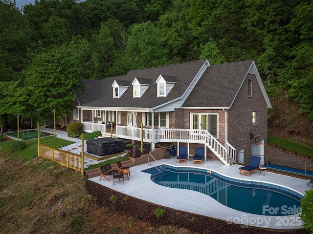 view of swimming pool featuring a wooden deck, a patio area, and a hot tub