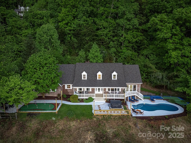 back of house featuring a swimming pool with hot tub and a lawn