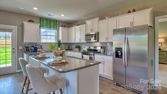 kitchen with a breakfast bar area, backsplash, white cabinets, and appliances with stainless steel finishes