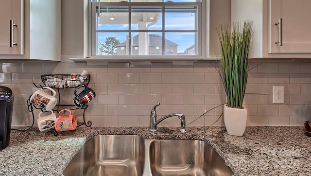 kitchen with decorative backsplash, white cabinets, light stone countertops, and sink