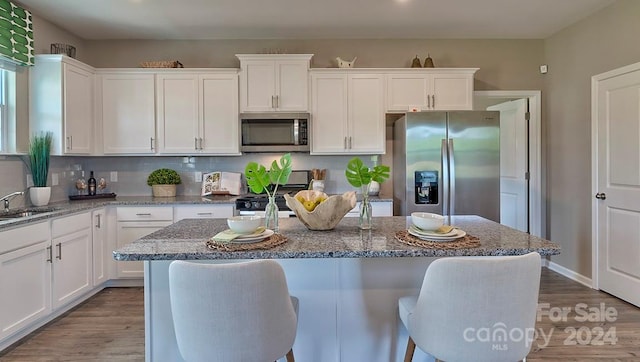 kitchen featuring white cabinetry, light stone counters, a center island, and appliances with stainless steel finishes