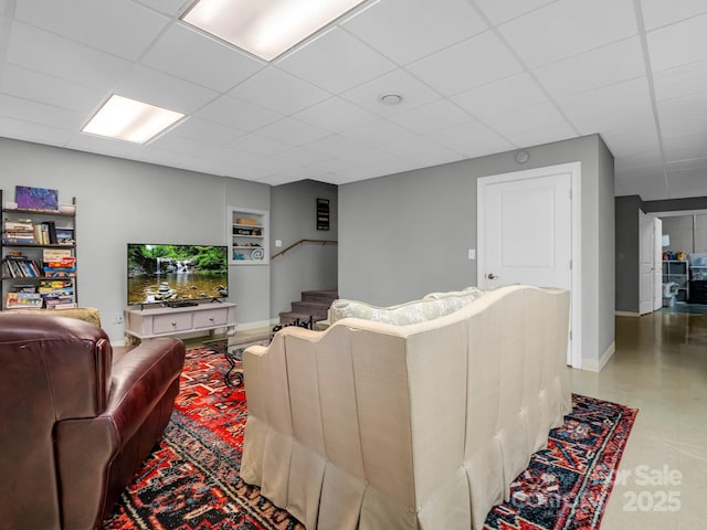 living room featuring built in features and a drop ceiling