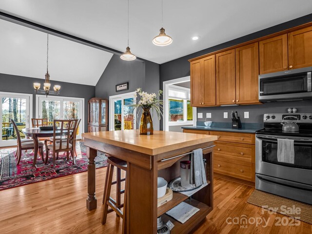 kitchen featuring decorative light fixtures, light wood-type flooring, appliances with stainless steel finishes, and a chandelier