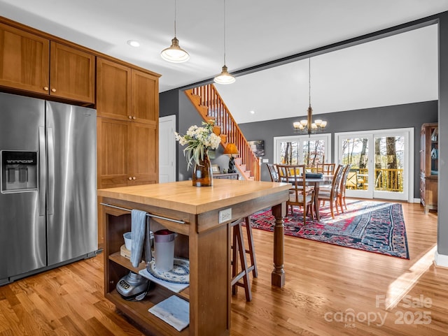 kitchen featuring wooden counters, an inviting chandelier, hanging light fixtures, light hardwood / wood-style flooring, and stainless steel fridge