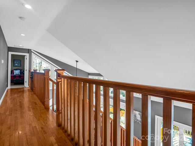 hallway with wood-type flooring and vaulted ceiling