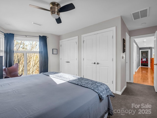 bedroom featuring carpet, ceiling fan, and multiple closets