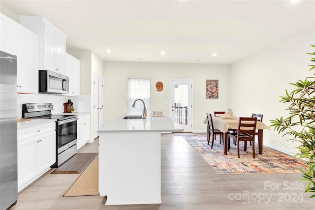 kitchen with a center island with sink, white cabinets, stainless steel appliances, and sink