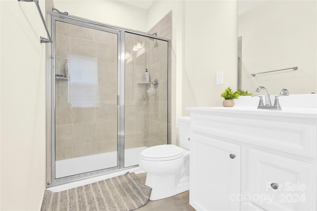 bathroom featuring tile patterned flooring, vanity, toilet, and walk in shower