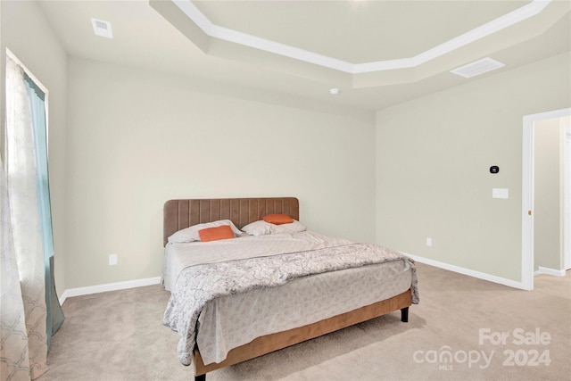 carpeted bedroom with ornamental molding and a tray ceiling