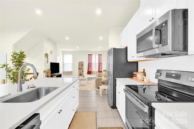 kitchen with white cabinetry, sink, light hardwood / wood-style floors, decorative backsplash, and appliances with stainless steel finishes